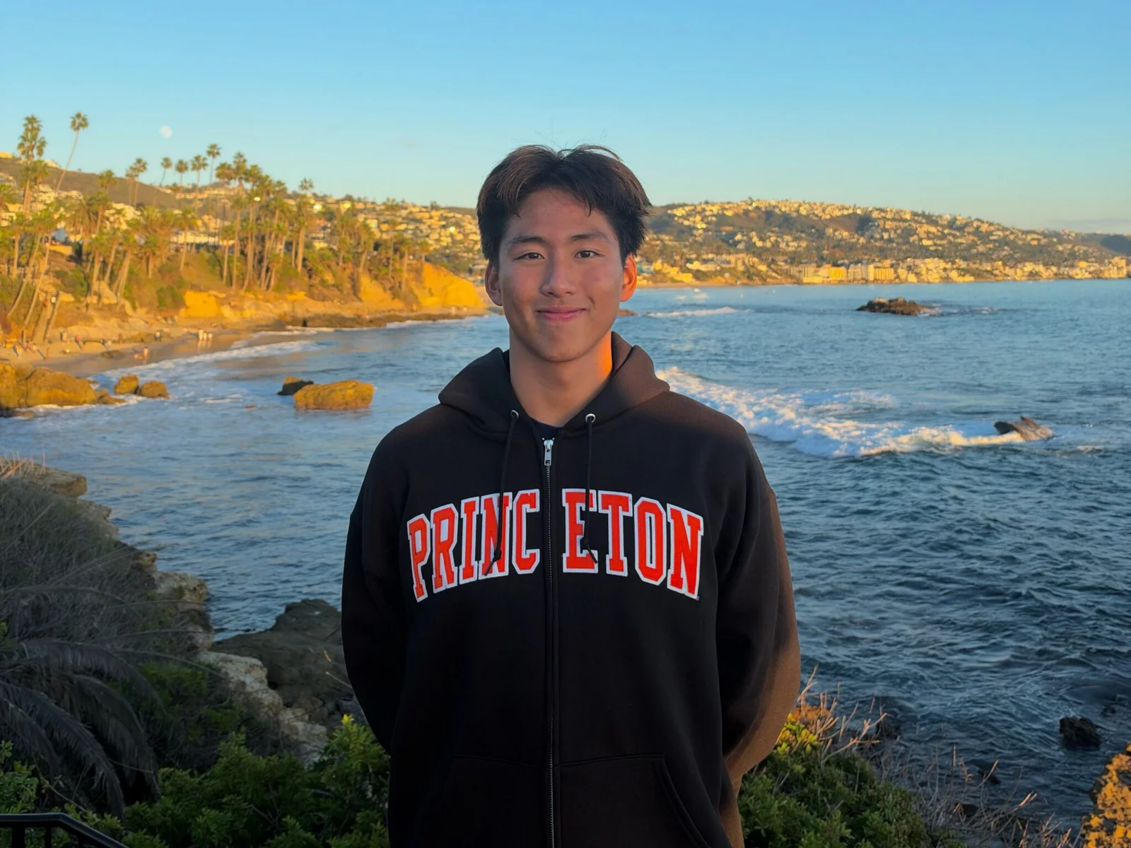 Michael Wang wearing a Princeton sweatshirt beside the ocean