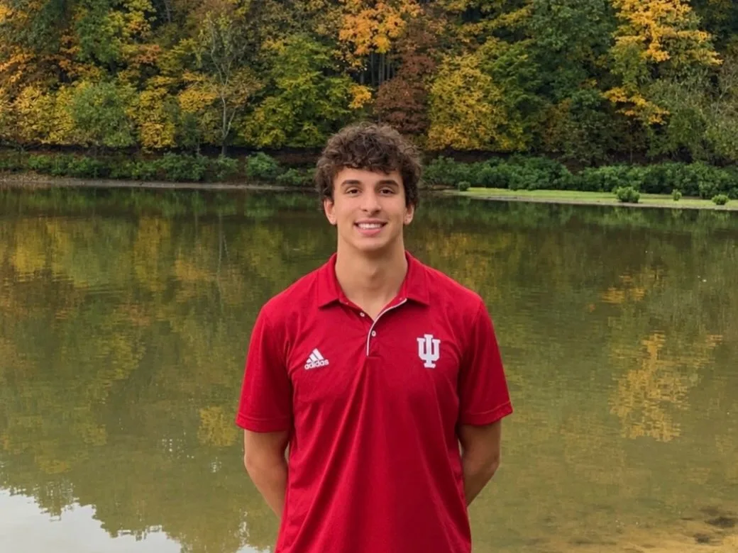 Peter Kovacs in an Indiana polo beside a tree-lined lake