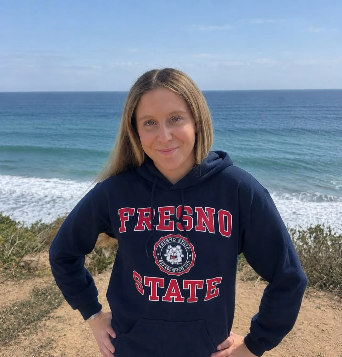 Wendy Zeiss wearing a Fresno State sweatshirt beside the ocean